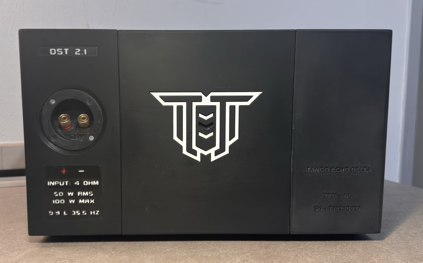 The back of the DST 2.1 prototype as it stood on the workbench, in front of a grey wall: terminals and a specification label on the left, the logo in the middle, name and serial number on the right.